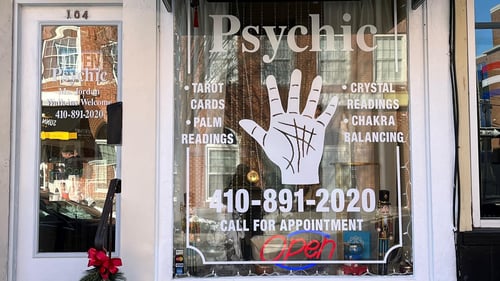 Front of Psychic of Bel Air Business showing front door & window with large hand image and phone 410-891-2020.