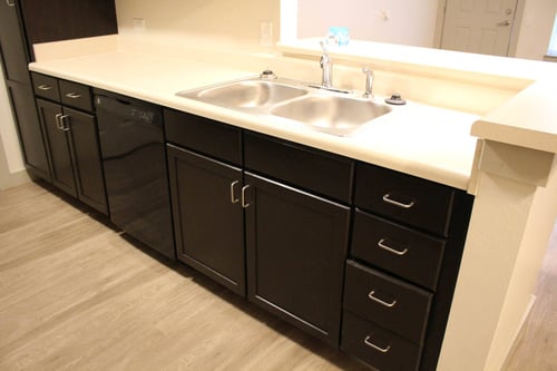 a kitchen with a stainless steel sink and black cabinets at Salem Place Apartments in Daleville, IN