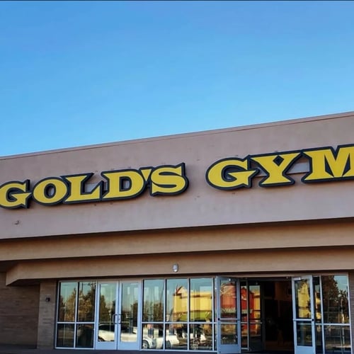 Exterior of Gold's Gym in Greeley, with the iconic yellow logo above the main entrance.