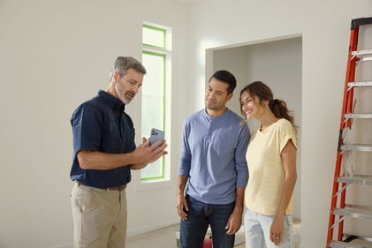 Installer showing couple the Kidde App for their smart devices.
