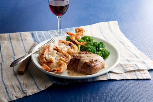 Steak, shrimp, and mashed potatoes with broccoli and a glass of wine
