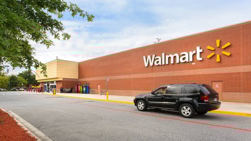 Black SUV passing by Walmart with a tree on the left side