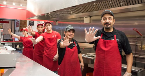 Group of restaurant employees in red uniforms with the text Our Crew. Our Family.