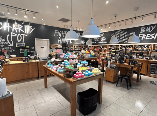 Interior view of shop. Various package and unpackaged products displayed on units along the walls, with 2 tables in the middle of the shop holding product displays.
