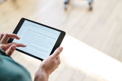 over the shoulder view of a person holding a tablet and reviewing content on screen