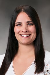 Brittany smiling in front of a gray background