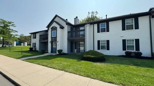 A white two-story apartment building with a black roof and a balcony on the second floor at Crooked Creek, Indianapolis, IN 46268