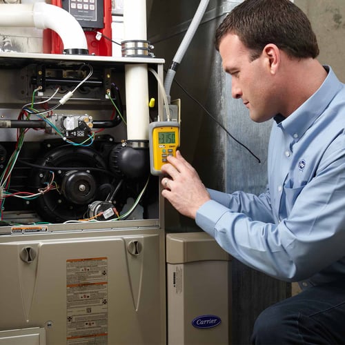 A Carrier dealer performs annual HVAC maintenance on a furnace