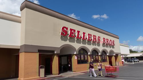 Two people with shopping cart in front of Sellers Bros. entrance