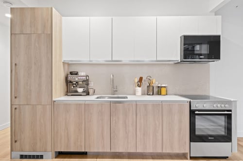 A modern kitchen with wooden cabinets and stainless-steel appliances at ARIA in New York City