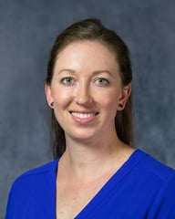 Amanda is smiling in front of a gray background.