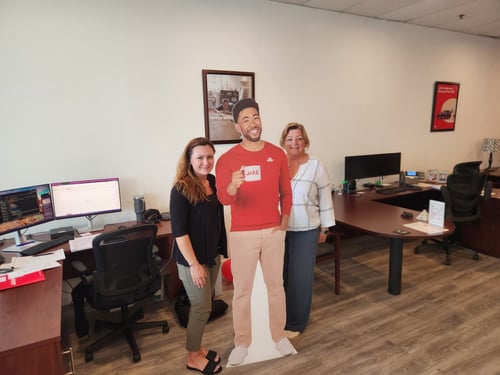 Two women standing on each side of a cardboard cutout man.