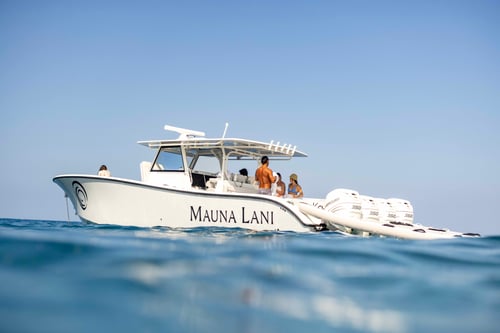 White boat with “Mauna Lani” written on the side on calm blue water.
