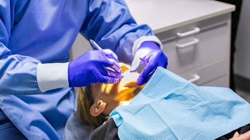 At Gentle Dental Springfield, a patient in a blue gown is having their teeth examined by a dentist.