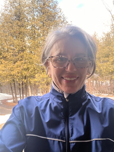 Selfie of Colleen on a sunny day infront of trees.