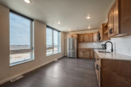 Living room with large windows and kitchen at Unite Apartments in Fargo, ND 58103