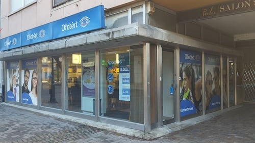 Ofotért üzlet homlokzata Vácon, a Széchenyi István utca 10. számnál, üvegportálos sarokbejárattal.