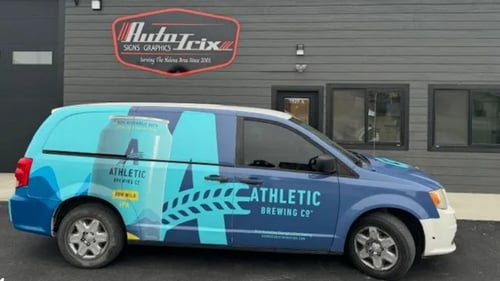 Custom wrapped vehicle in front of Auto Trix Signs and Graphics logo