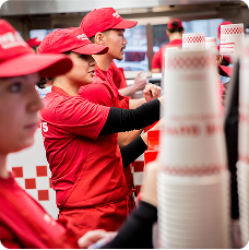 A collection of red uniformed restaurant crew members working and smiling.
