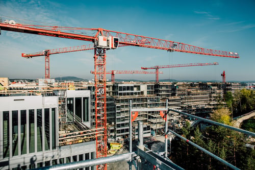 Kranen rund um eine Baustelle mit Hochhäusern.