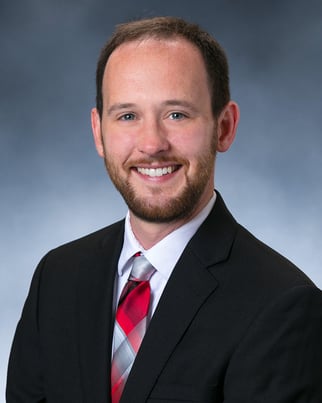 Dr. Joseph Benert smiling in front of a gray background.