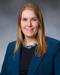 Cheryl Mansell smiling in front of a gray background.