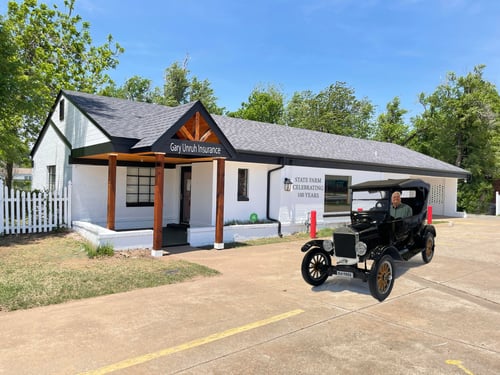 White building with black rood and old car out front