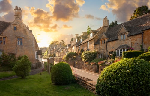 Row of houses in the cotswolds with greenery and a sunset