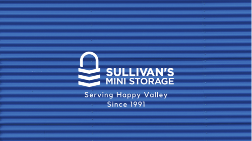 Close-up of dark blue roll-up door with superimposed, stylized, white padlock logo and text reading, "Sullivan's Mini Storage. Service Happy Valley Since 1991."