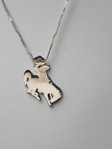 The Golden Buffalo Fine Jewelry Large Cowboy Necklace Sterling Silver The Bucking Horse and Rider silhouette, recognizable from Wyoming's license plates and the University of Wyoming, is produced by Golden Buffalo® Fine Jewelry as part of their exclusive trademark license agreement.