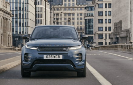 Dark blue Range Rover driving across a city bridge with modern buildings in the background