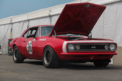 An old red car with the hood opened.