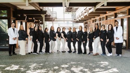 Group photo of the dental office staff standing together outdoors in front of the practice