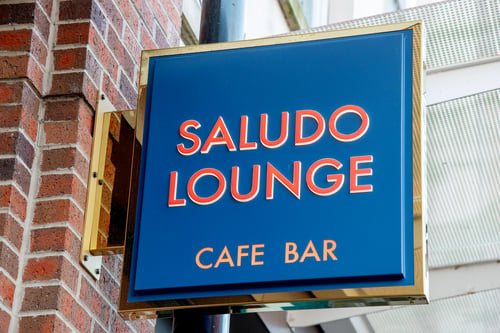 Saludo Lounge Cafe Bar written in red on a dark blue square sign