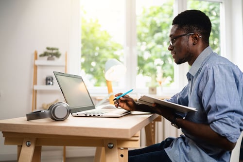Man sitting at desk with book and pencil in hands