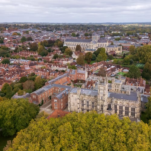 Knight Frank Winchester Estate Agents - Aerial view of Winchester College Chapel in the foreground, with Winchester Cathedral visible in the distance across the cityscape
