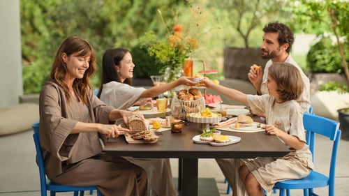 Eine Familie genießt ein entspanntes Frühstück im Freien. Frisch gebackenes Brot, Croissants und Brötchen stehen auf dem Tisch. Morgengold bringt regionale Backwaren frühmorgens an die Haustür – bequem, zuverlässig und mit höchster Qualität.