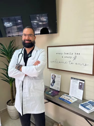 Images of a doctor inside of the clinic. He is standing in front of a tv and there is a table with informational brochures to his right.