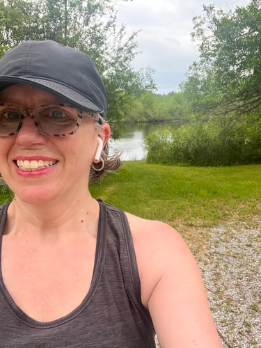Selfie of Colleen by the water surrounded by greenery and blue skies