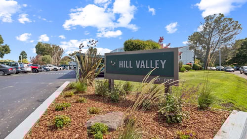 A sign that says Hill Valley in front of a parking lot