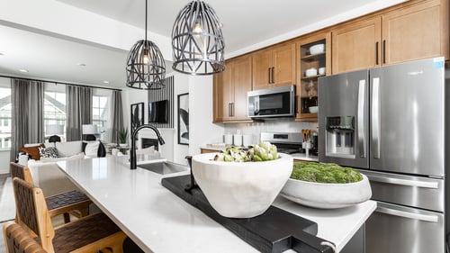 DRB Homes Huntfield Townhomes kitchen with natural wood cabinets, stainless steel appliances and white island.