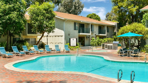 A swimming pool with a house in the background at Village Pointe Apartments, California