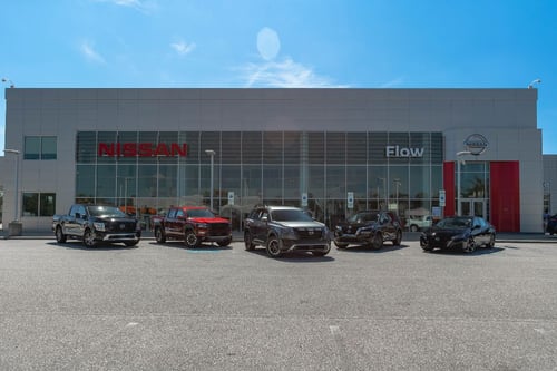 Nissan dealership in Fayetteville NC with variety of new Nissan cars, trucks and SUVs lined up in front