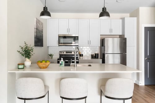 A kitchen with white cabinets and a stainless steel refrigerator at Junction at Fayetteville, Fayetteville, AR.