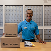 The UPS Store associate with mail in front of mailboxes