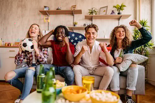 Group of friends sitting on couch cheering for game