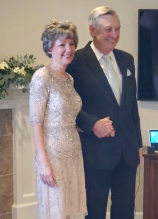 Woman in wedding dress holding hands with a man in tuxedo during wedding ceremony