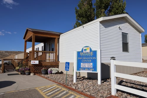 Information Center Exterior with white walls and a blue sign that says "Skyline Village" in front
