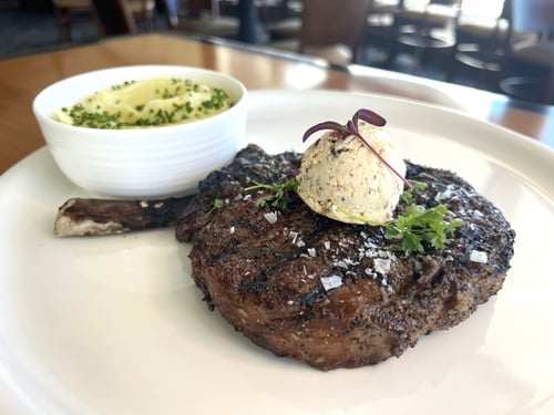 Photo showing a 16oz bone-in ribeye accompanied by truffle whipped Yukon potatoes.