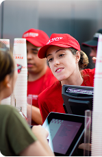 A collection of red uniformed restaurant crew members working and smiling.